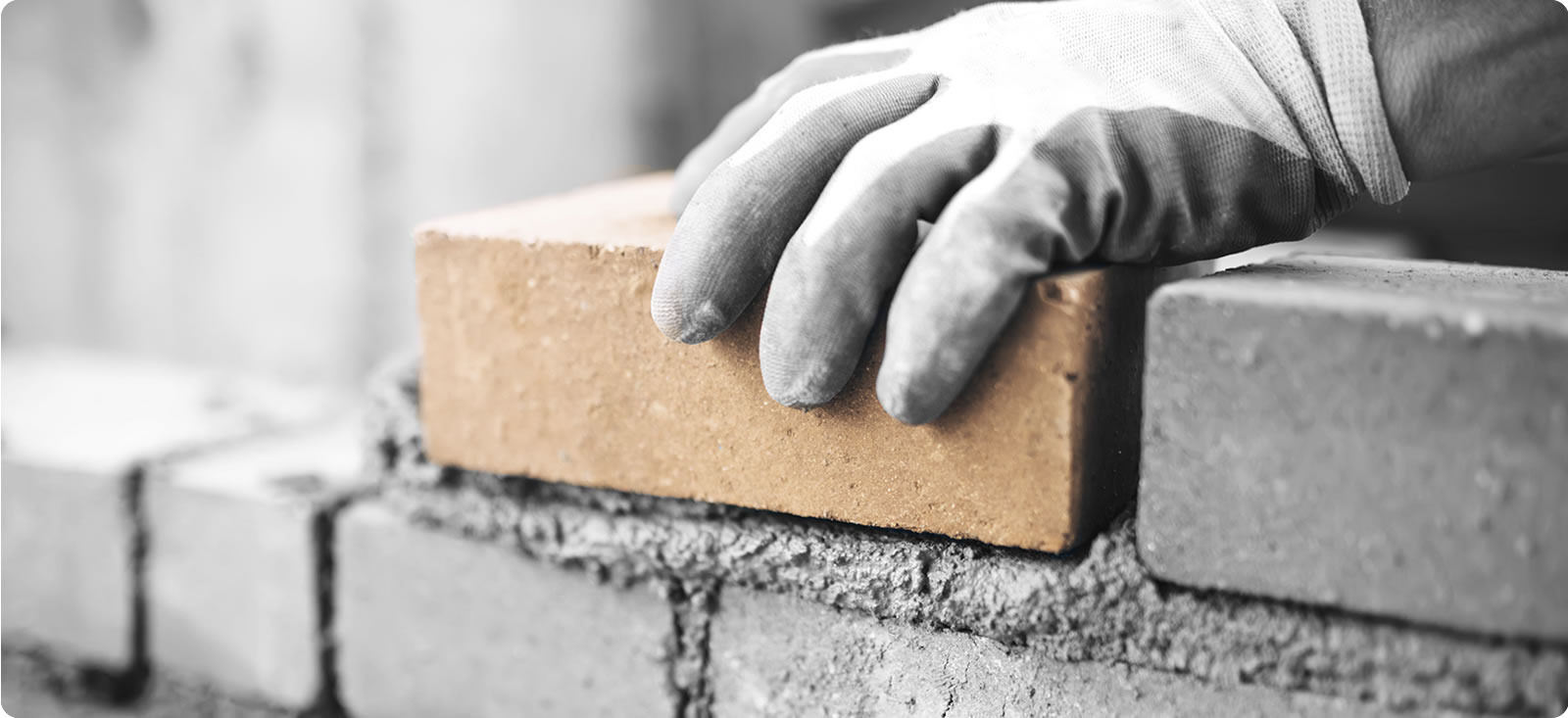 Hand laying brick on wall